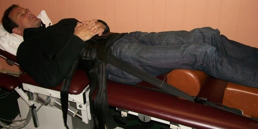Patient relaxing on a spinal decompression table with padded straps