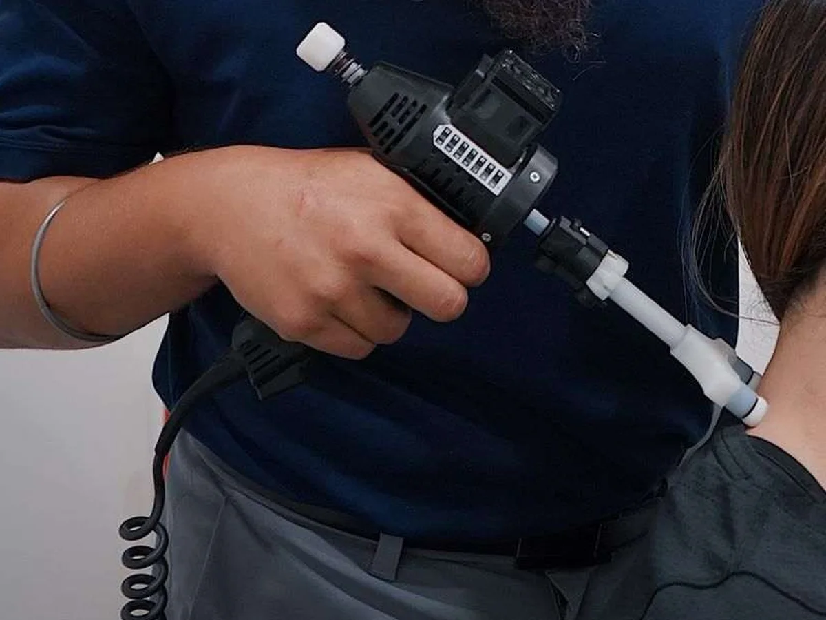 Chiropractor using an Impulse adjusting instrument at a patient's neck