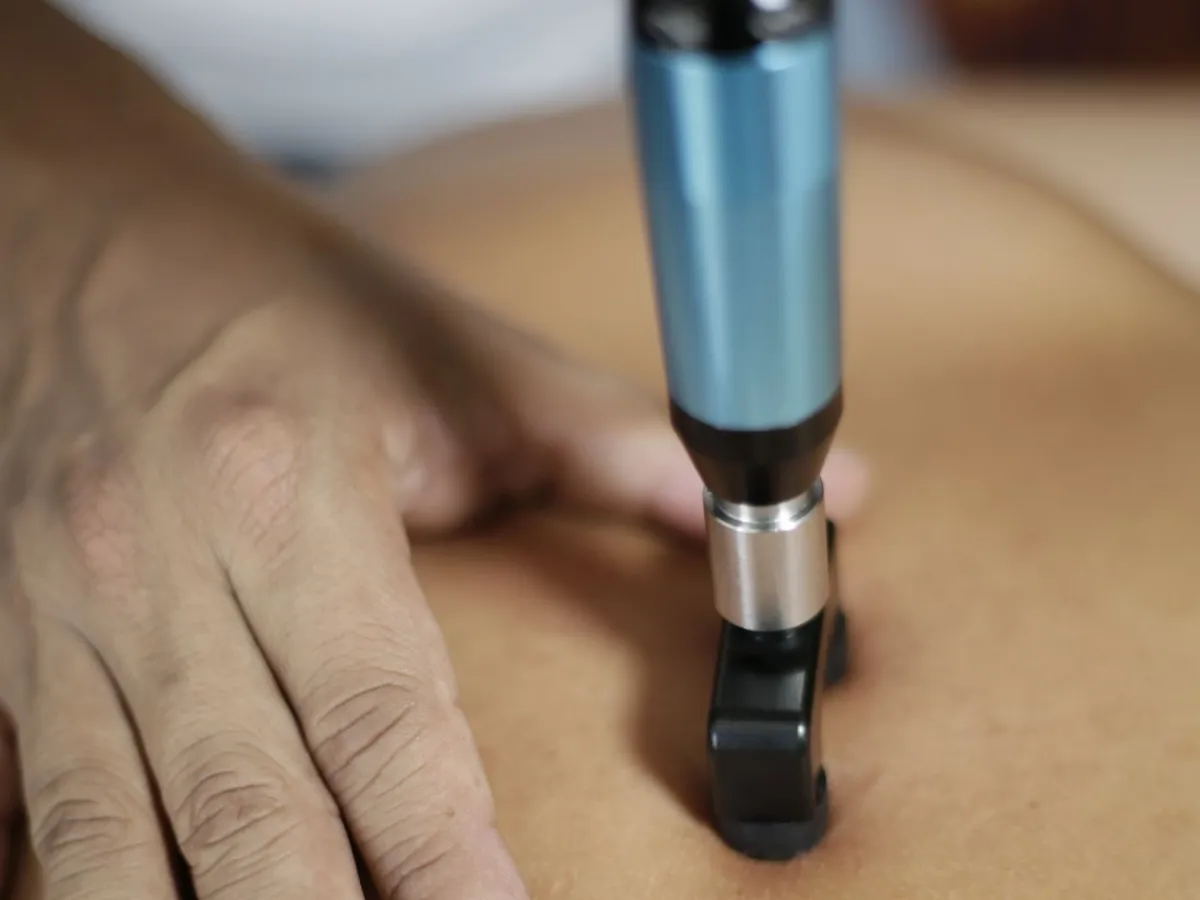 Practitioner using a handheld adjusting instrument on a patient's back